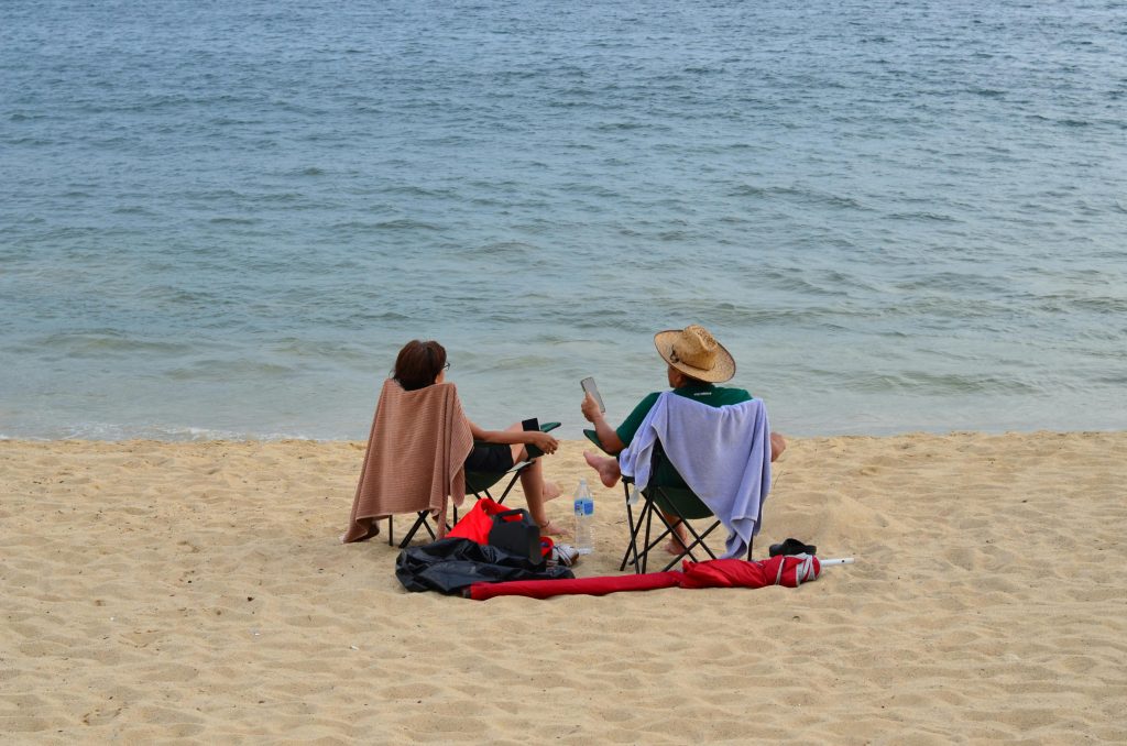 Person meditating at the beach to reap health benefits of travel