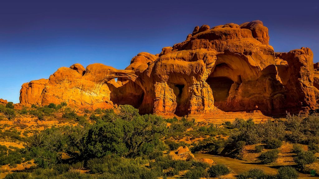 Sunset light over red rock formations in Arches National Park desert landscape